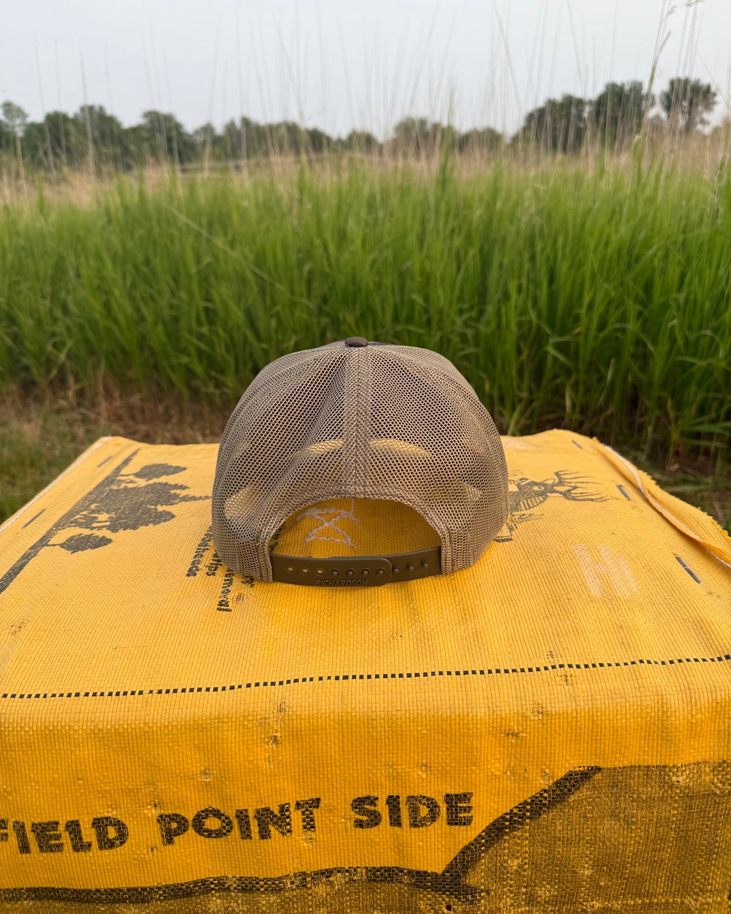 Gray cap on a yellow bag with 'Field Point Side' text in a grassy field