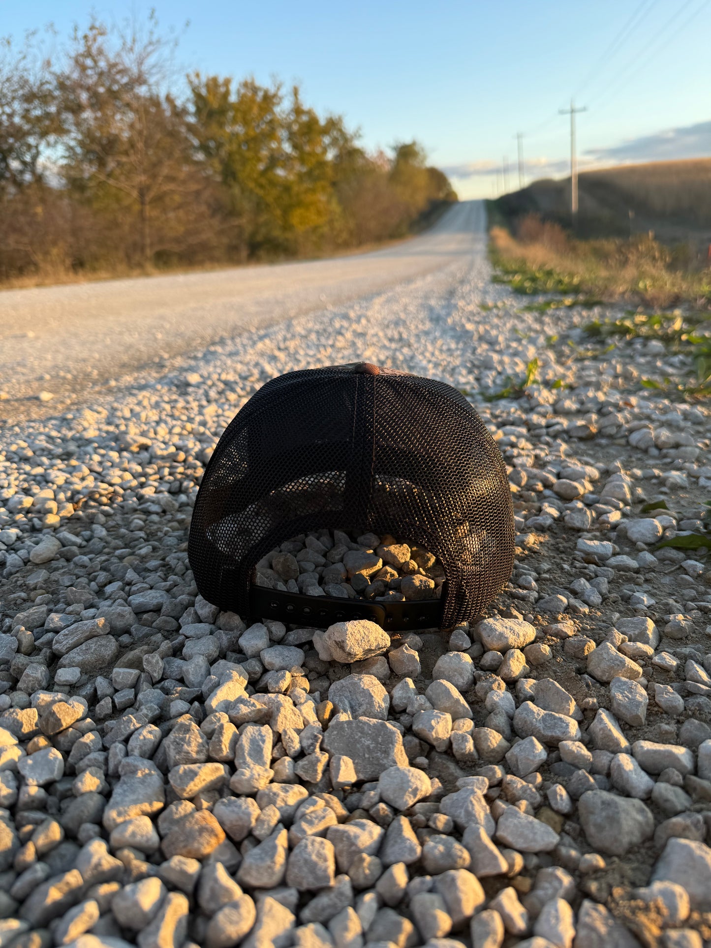Black Hat on a gravel road with trees in the background