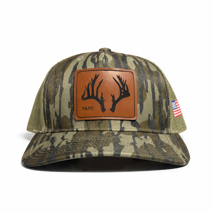Camouflage baseball cap with leather patch and American flag on a white background