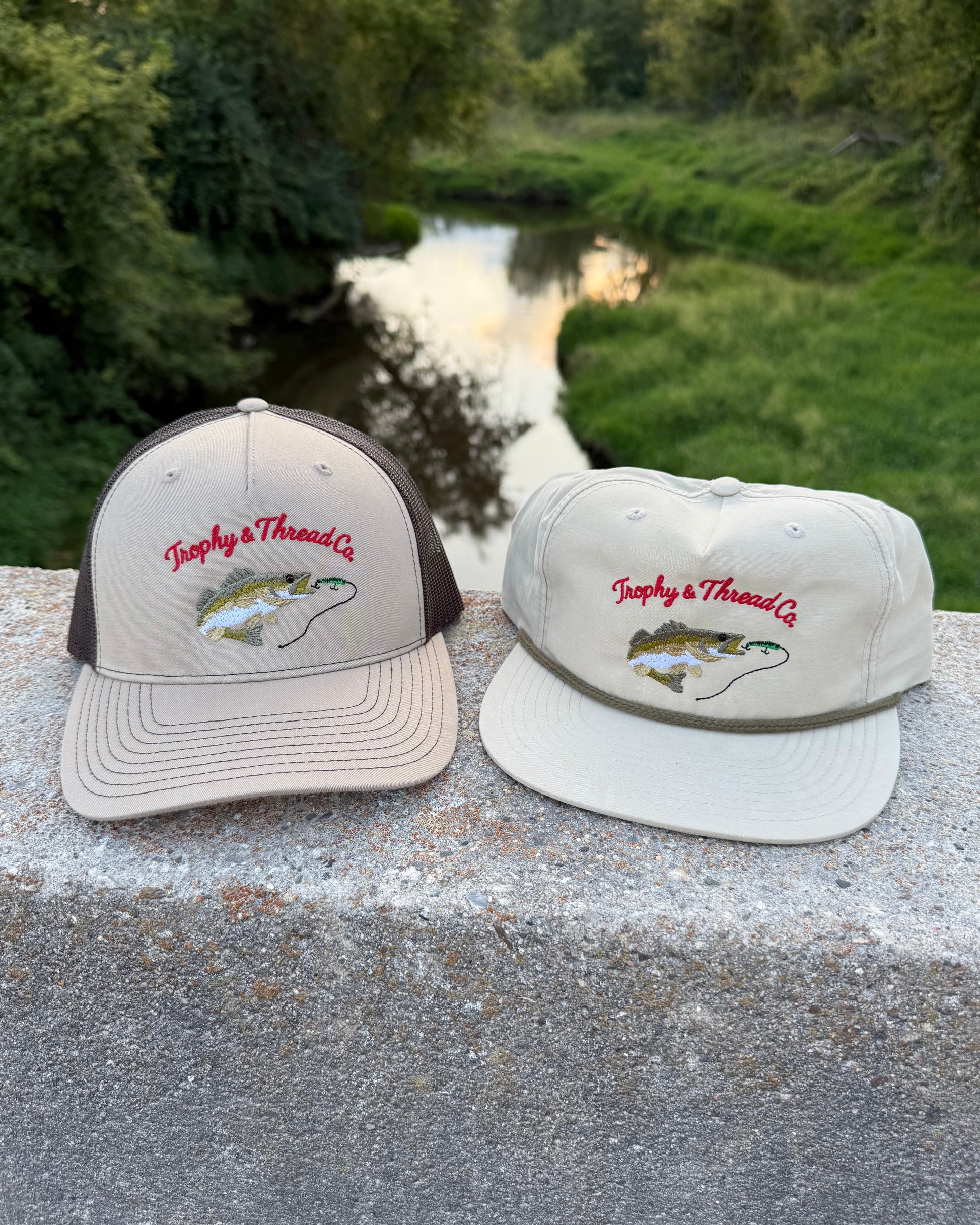 Hats with Trophy and Thread Co Walleye design on a stone ledge by a river. Walleye Hat